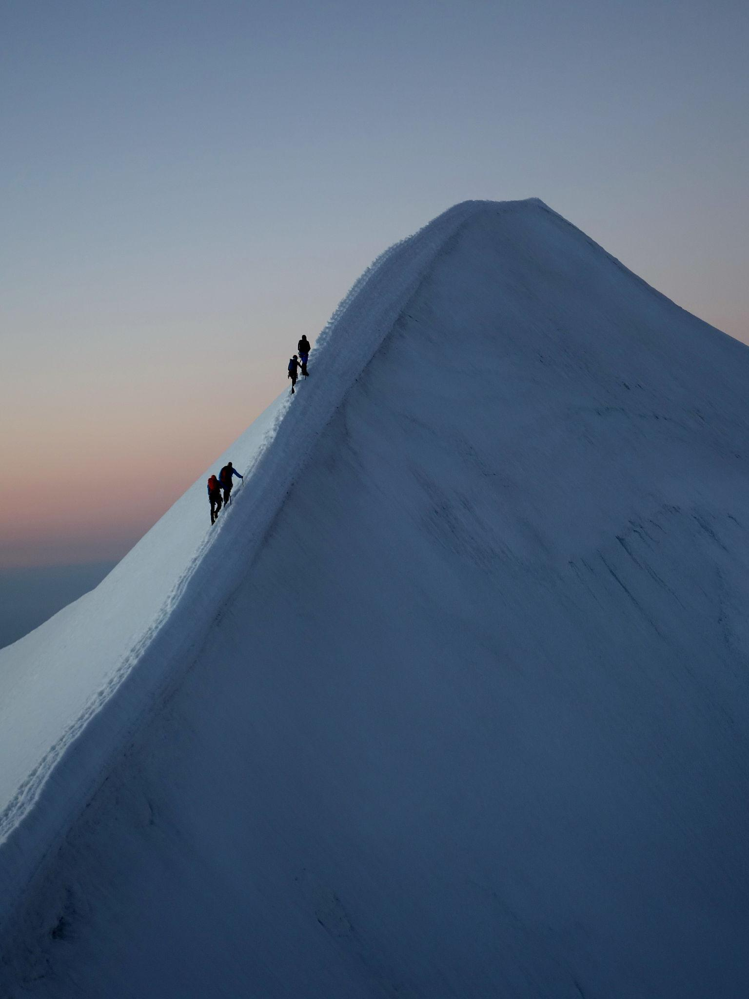 Cordée en progression sur une arête enneigée, métaphore du passage Sherpa